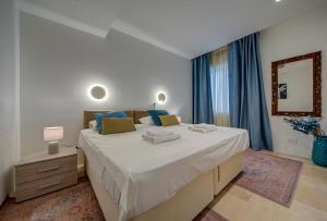 a bedroom with a large bed with blue curtains at Vista Laguna - Harbour View - Private Jacuzzi in Għajnsielem