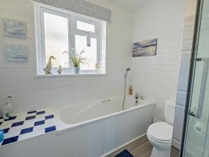 a bathroom with a tub and a toilet and a window at 3 Bed in Ventnor oc-89972 in Niton +14 photos