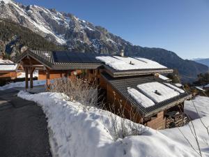 a house covered in snow with a mountain in the background at Chalet Orchidée by Interhome in Ovronnaz