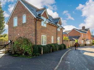 a man on a horse walking in front of a house at 3 Bed in Lymington oc-90002 in Sway
