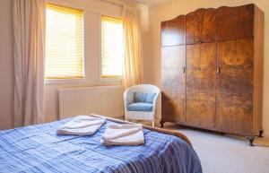 a bedroom with a bed with a dresser and a chair at The Blue Lobster in Drynoch