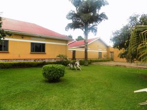 a yard with a yellow house and a tree at Rhino Motel Mbarara in Mbarara