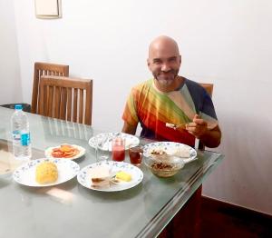 a man sitting at a table with plates of food at Maya Residency in Alleppey