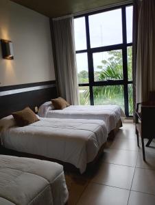 two beds in a hotel room with a large window at Maria's Hotel in La Banda +108 photos