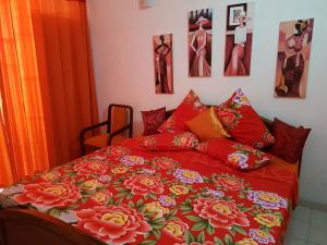 a bed with a red comforter with flowers on it at Thambili Island @ Stubbs in Colombo