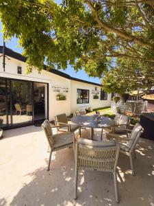a patio with a table and chairs under a tree at Lagoon Haven House in Hermanus