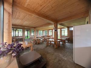 a large room with wooden tables and a refrigerator at Hotel Roba in Ureki