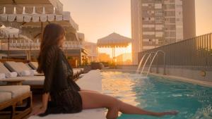 a woman sitting on the edge of a swimming pool at The Cole Boutique Hotel & Spa in Cape Town