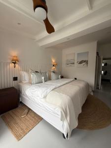 a bedroom with a large white bed with a ceiling at Lagoon Haven House in Hermanus +40 photos