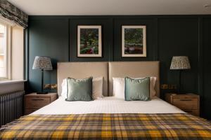 a bedroom with a bed with green walls and two lamps at The White Hart in Stockbridge