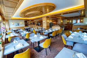 a restaurant with blue tables and yellow chairs at Best Western Plus Au cheval Blanc à Mulhouse in Baldersheim