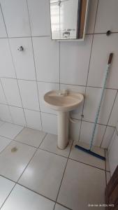 a white bathroom with a sink and a mirror at Pousada Itararé in São Vicente