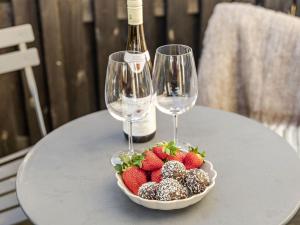 a bowl of strawberries and two wine glasses on a table at Apartment Vårhemsplatsen by Interhome in Halmstad