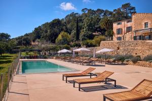 a pool with chairs and umbrellas next to a building at Finca Son Cladera in Sa Pobla
