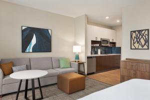 a living room with a couch and a table and a kitchen at Staybridge Suites Rockford by IHG in Rockford