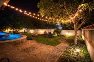 a backyard with a tree with lights and a pool at Family House FreeДом in Sinemorets