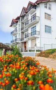 a white apartment building with flowers in front of it at 7 Crowns Villa Ambewela, Nuwara Eliya in Boragasketiya