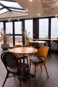 a restaurant with tables and chairs and windows at Hôtel La Frégate in Fécamp