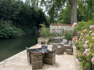 a patio with chairs and a table next to a river at Le Clos de l'Armançon - Maisons de charme au bord de la rivière - Classé 4 étoiles in Tonnerre