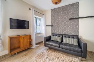 a black leather couch in a living room with a tv at L'Expresso in Frontonas +4 photos