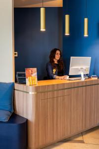 a woman sitting at a counter with a laptop at Hôtel Café Miramar in Le Grau-du-Roi