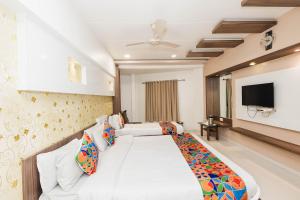 a hotel room with a bed and a flat screen tv at Hotel Amber Railway station in Vadodara