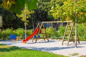 a playground with a slide and a swing at MASLINICA Oliva Camping Pitches in Rabac