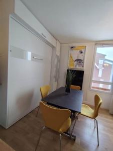 a dining room with a black table and yellow chairs at Le 4 Saisons in Ustou