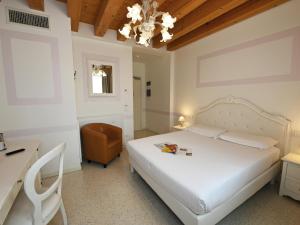 a bedroom with a bed and a desk and a chair at Hotel Villa Patriarca - Buongiorno! Hotels in Mirano