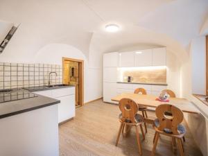 a kitchen with white cabinets and a wooden table and chairs at Apartment Chesa Treig by Interhome in Samedan +4 photos