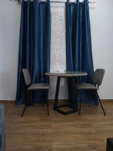 a table and two chairs in a room with blue curtains at CJ apartment kasoa in Kasoa
