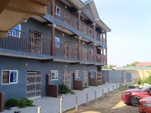 a building with balconies and cars parked in a parking lot at CJ apartment kasoa in Kasoa