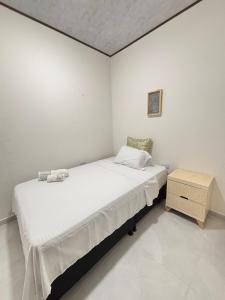 a white bedroom with a bed and a night stand at Aparta Hotel La Osadía in Acacías