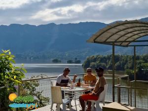 Drei Personen sitzen an einem Tisch mit Blick auf einen See in der Unterkunft Pradolago Sol Prado Tolima in Prado