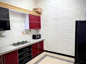 a small kitchen with red cabinets and a black refrigerator at House No 6, Valley Homes in Pothi