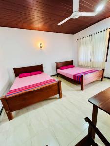 two beds in a large room with a table at Flourish holiday resort in Kataragama