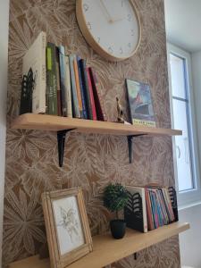 a clock on a wall above a shelf with books at Parenthèse en Savoie in Albertville