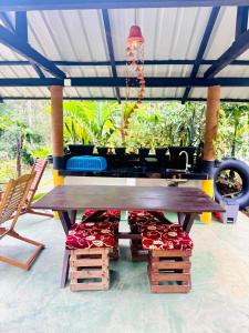 a wooden picnic table with chairs and a chandelier at Rainforest Tea Garden Cabin-River View in Deniyaya +8 photos
