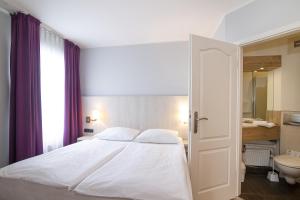 a bedroom with a white bed and a bathroom at Nautic Hotel Bremerhaven in Bremerhaven
