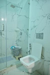 a white bathroom with a toilet and a shower at hotel tripta ganga in Rishīkesh