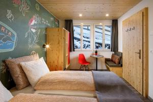 a bedroom with a bed and a red chair at Eiger Guesthouse in Mürren +46 photos