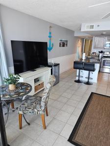 a living room with a flat screen tv and a kitchen at Beachfront Condo Panama City Beach Gulf Front Views walk to Pineapple Willy's in Panama City Beach