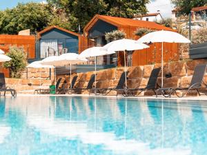 a swimming pool with umbrellas and chairs and a pool at Wine Paradise - Glamping resort in Marezige