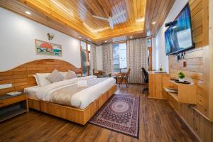 a bedroom with a large bed and a flat screen tv at Hotel SNAS Retreat Manali in Manāli