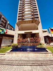 a building with a fountain in front of a building at Suite master, condo-hotel in Joinville