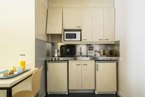 una pequeña cocina con armarios blancos y microondas en Residencia Universitaria Erasmo, en Madrid
