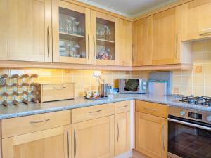 a kitchen with wooden cabinets and a counter top at Orchard Mews , Barnham in Barnham