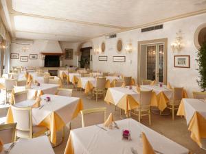 a restaurant with white tables and yellow chairs at Hotel Villa Patriarca - Buongiorno! Hotels in Mirano