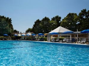 a swimming pool with chairs and umbrellas at Hotel Villa Patriarca - Buongiorno! Hotels in Mirano