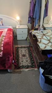 a bedroom with a bed and a rug and a table at BIDWILL GARDENS ON MIDDLETON - 2 Rooms A Private Room with a King-Size Bed or Open Lounge Room Floor Mattress SHARED Bathroom FREE Kitchen Essentials FREE Laundry Facilities Fast WIFI HDTV NETFLIX, YOUTUBE, KAYO Meal and Transport Services Available in Bidwill